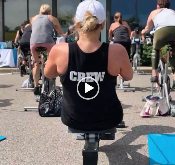 A woman is riding an exercise bike in front of other people.