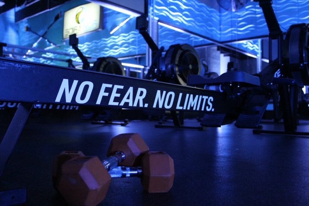 A gym with no fear, no limits sign and two dumbbells.