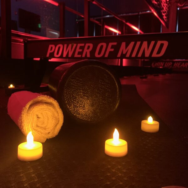 Candles are lit on the ground in front of a power of mind sign.