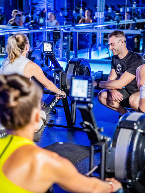 A group of people in the gym on rowing machines.